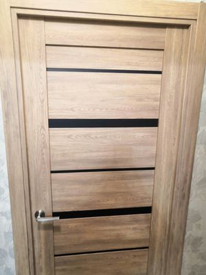 Установлена новая деревянная створка, закреплены петли, врезан замок, смонтирована ручка, отрегулированы зазоры, проверена плавность хода, выполнена отделка проема, завершены все монтажные работы.