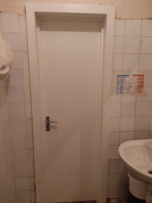 На белой двери установлен замок с ручкой. Проведены работы по вырезанию отверстия, монтажу механизма и фиксации. Дверь закрывается плавно, механизм функционирует исправно.